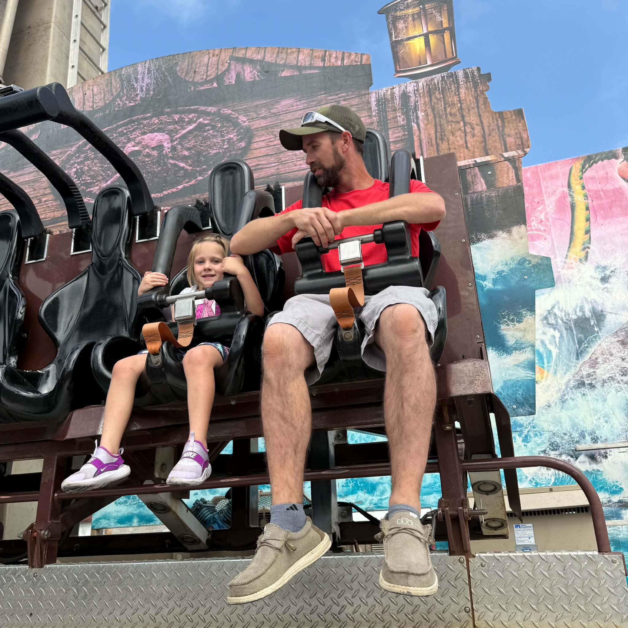 A father and young daughter riding an outdoor roller coaster at the Wo-Zha-Wa carnival
