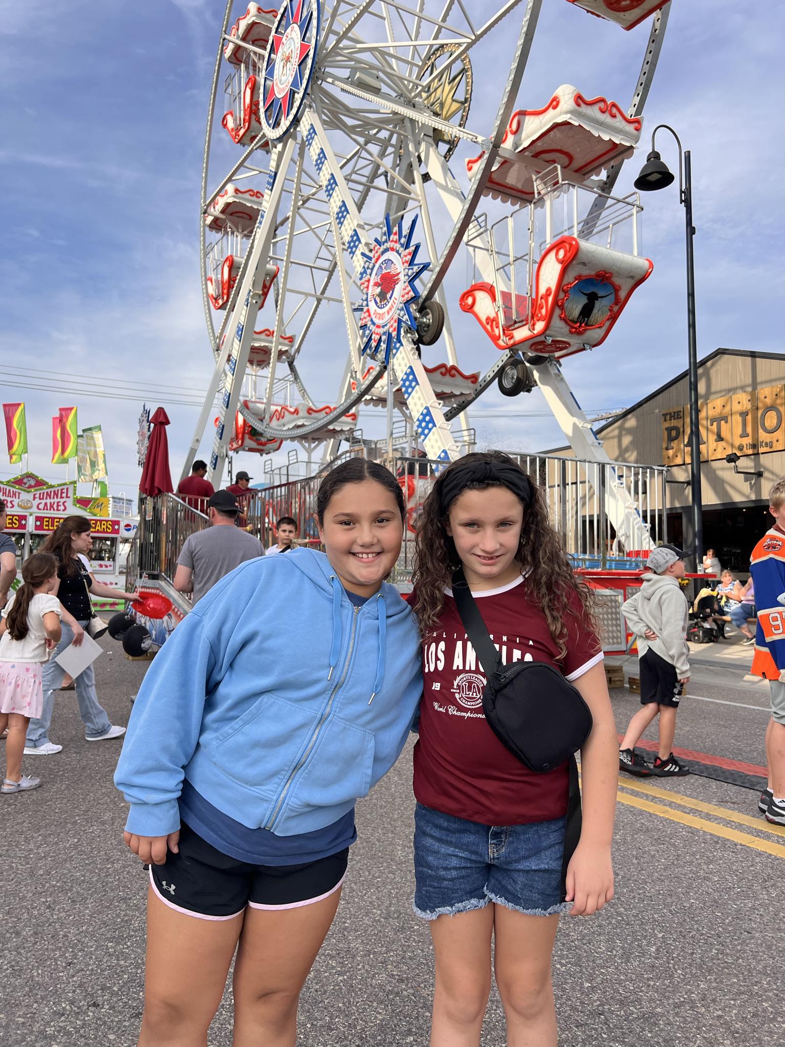Two friends standing in front of the festival Ferris wheel