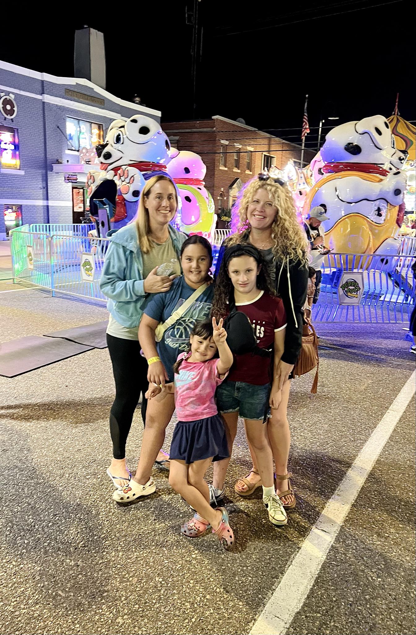 A family posing together beside illuminated carnival rides at night