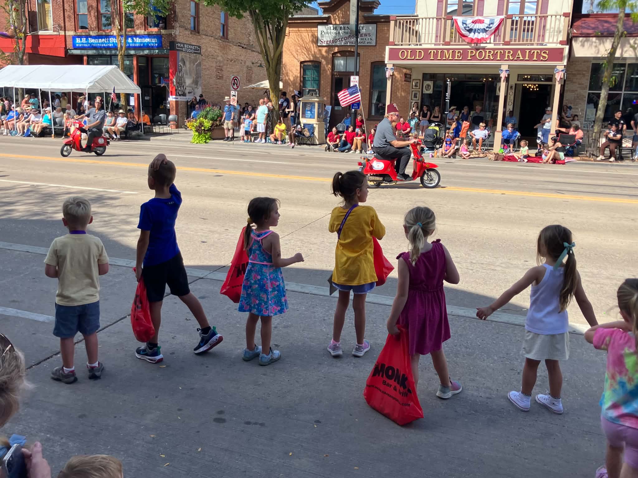 Children watching miniature cars travel along the downtown parade route